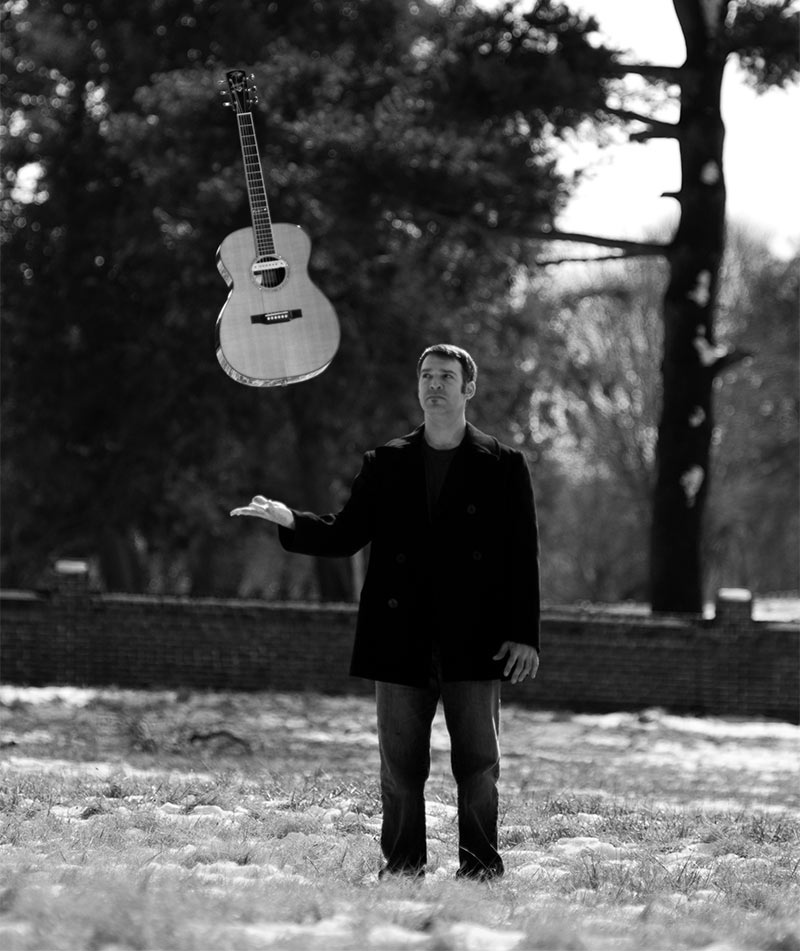 Black and white portrait of Sam Pacetti tossing his guitar